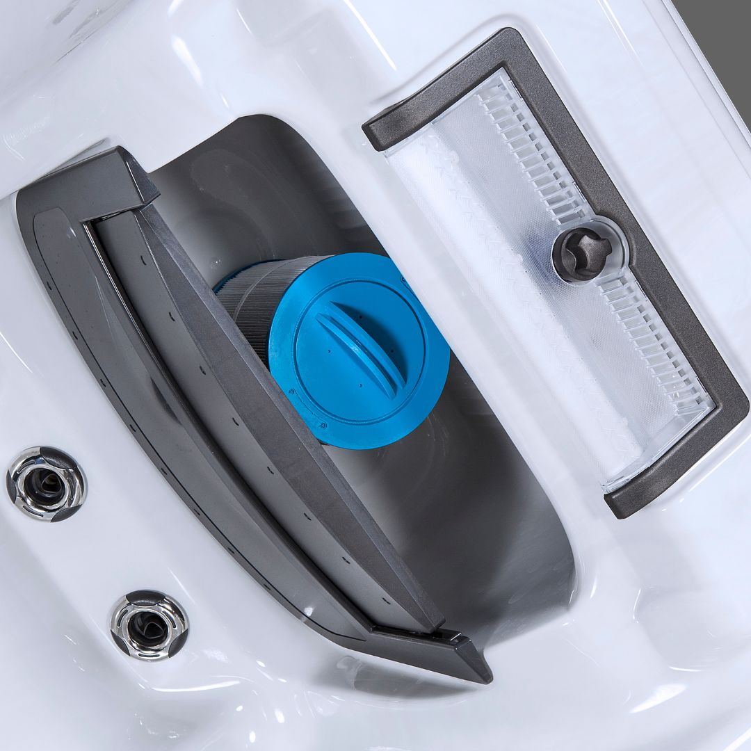 A blue Artesian Spa filter cartridge with a handle installed inside the built-in filtration skim filter housing of a white hot tub shell.