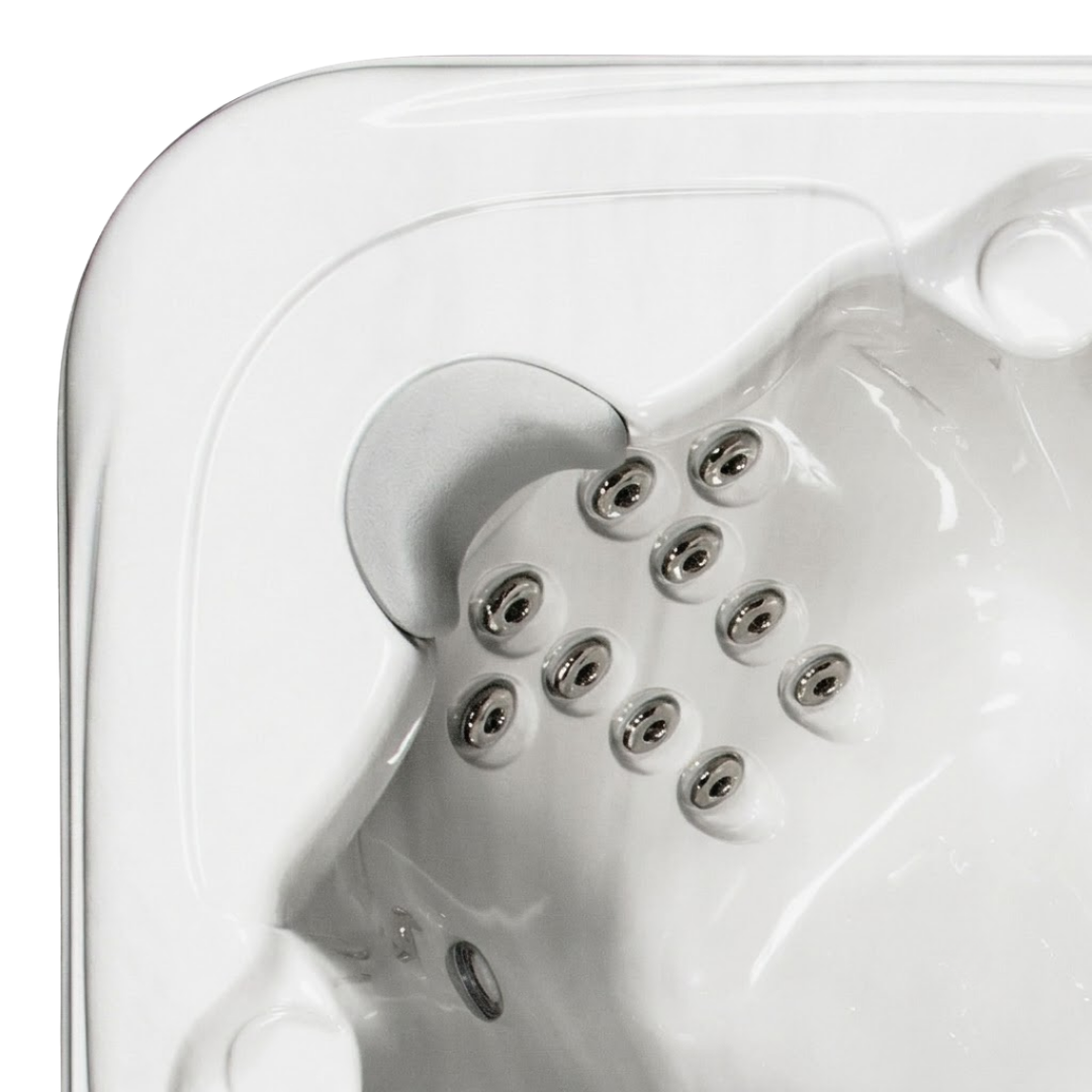 Overhead view of an Artesian Spas South Seas series light gray neck headrest pillow installed in the corner seat of a white acrylic hot tub, situated above a configuration of stainless steel hydrotherapy jets.