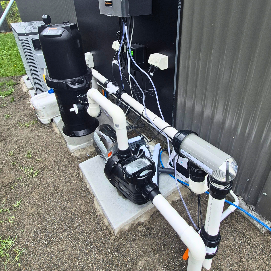 Outdoor residential pool equipment installation featuring an AstralPool Viron P320XT eVo variable speed pump connected via white PVC pipework to a cartridge filter and chlorinator cell on a concrete pad next to a corrugated wall.