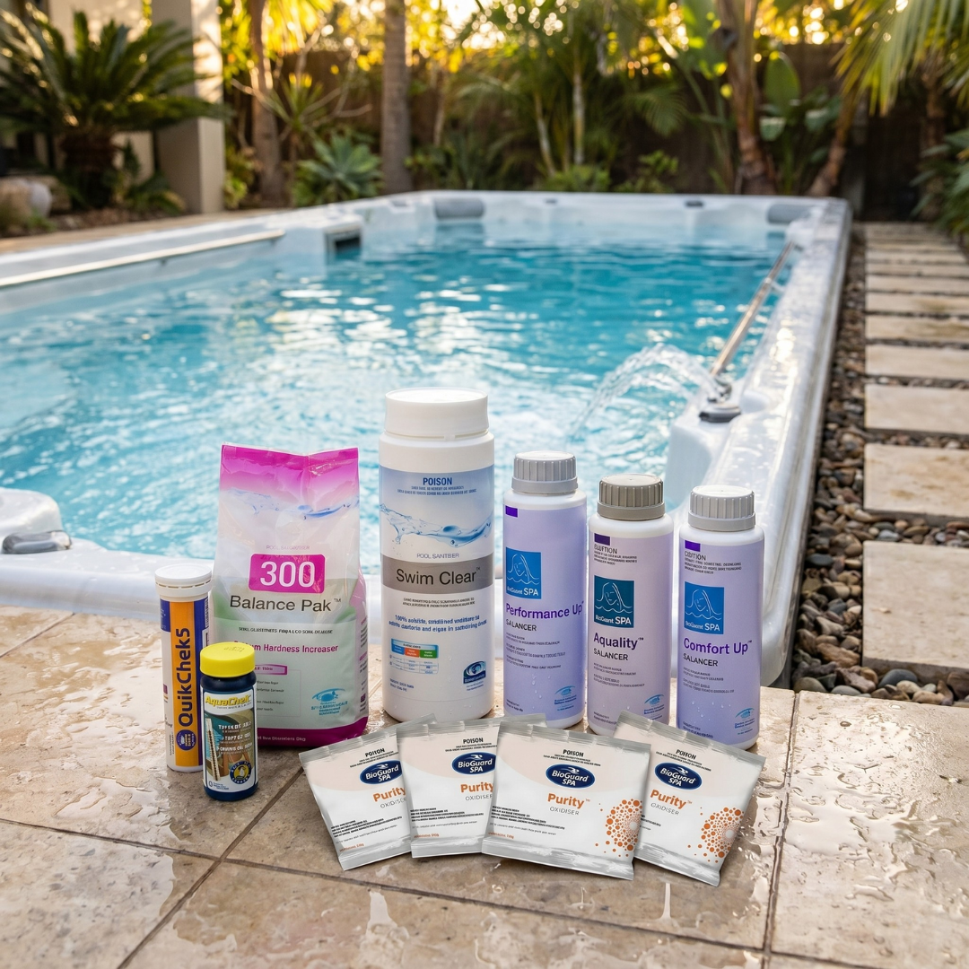 BioGuard SaltSwim plunge pool and spa water treatment chemical kit, including Swim Clear, Balance Pak 300, Performance Up, Aquality, Comfort Up balancers, Spa Purity sachets, and AquaChek test strips arranged on a stone pool ledge next to a backyard plunge pool.