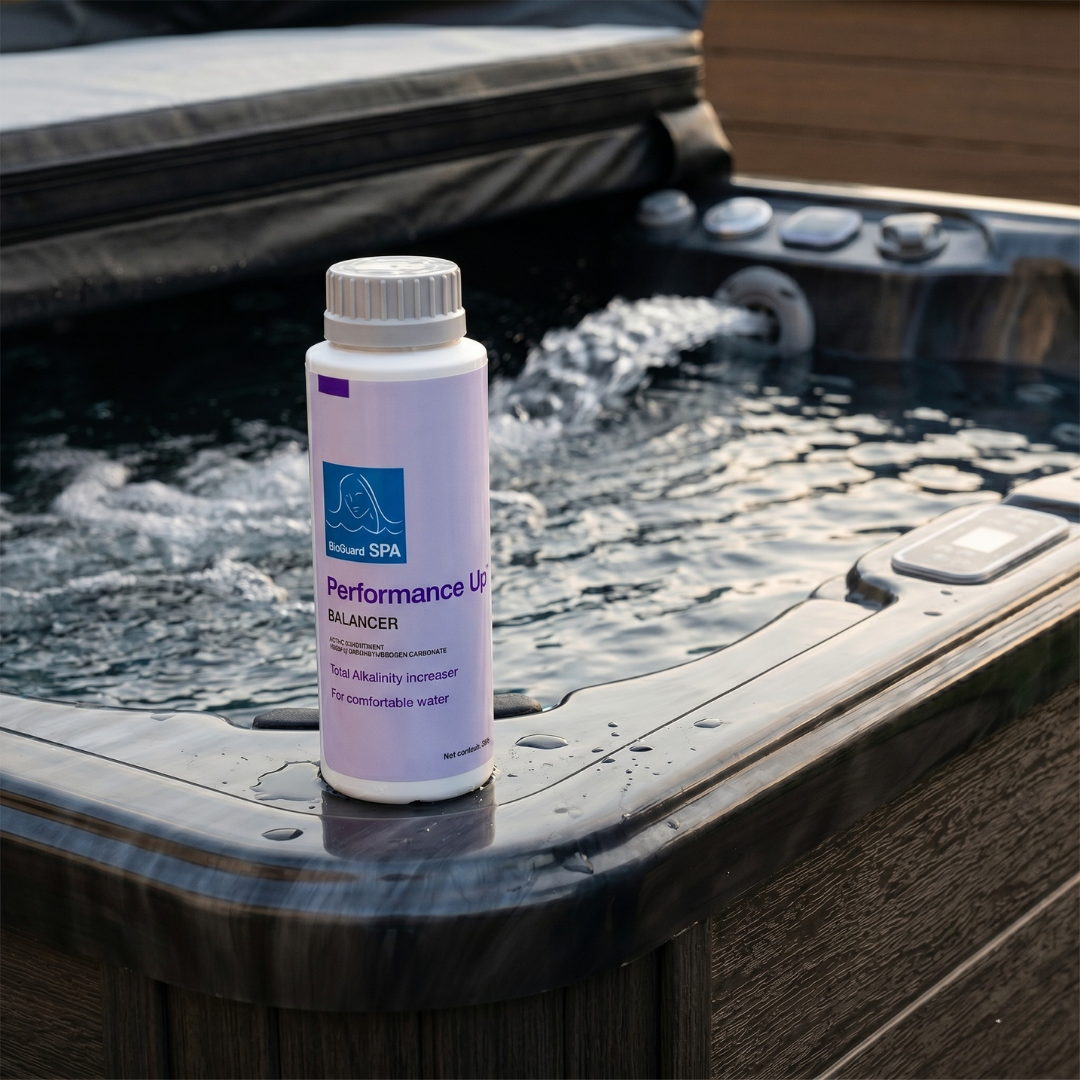 A 500g bottle of BioGuard Spa Performance Up Total Alkalinity Increaser on the edge of a dark grey hot tub with running water jets, used to stabilize pH and improve water comfort.