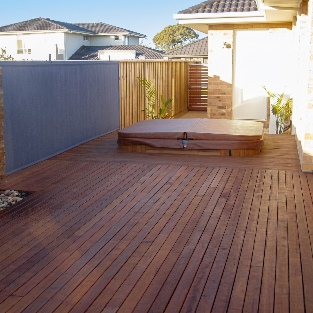 A closed brown custom hot tub hard cover installed on an inground spa built into a spacious timber entertainment deck.