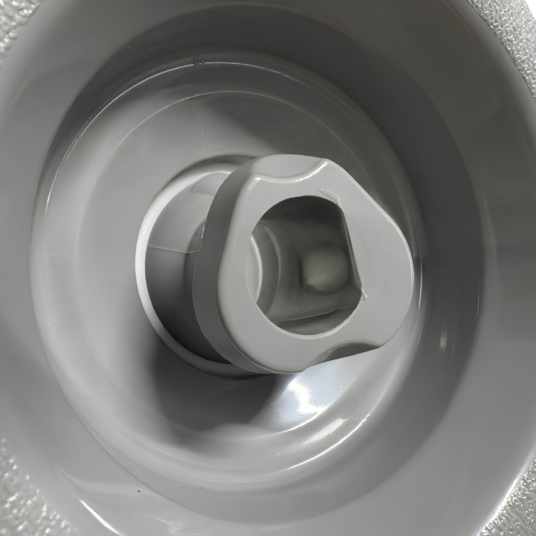 Close-up view of the central rotational nozzle on a grey Cyclone adjustable swirl spa jet internal insert, showing its shaped fluid outlet housed within a smooth circular inner bezel.