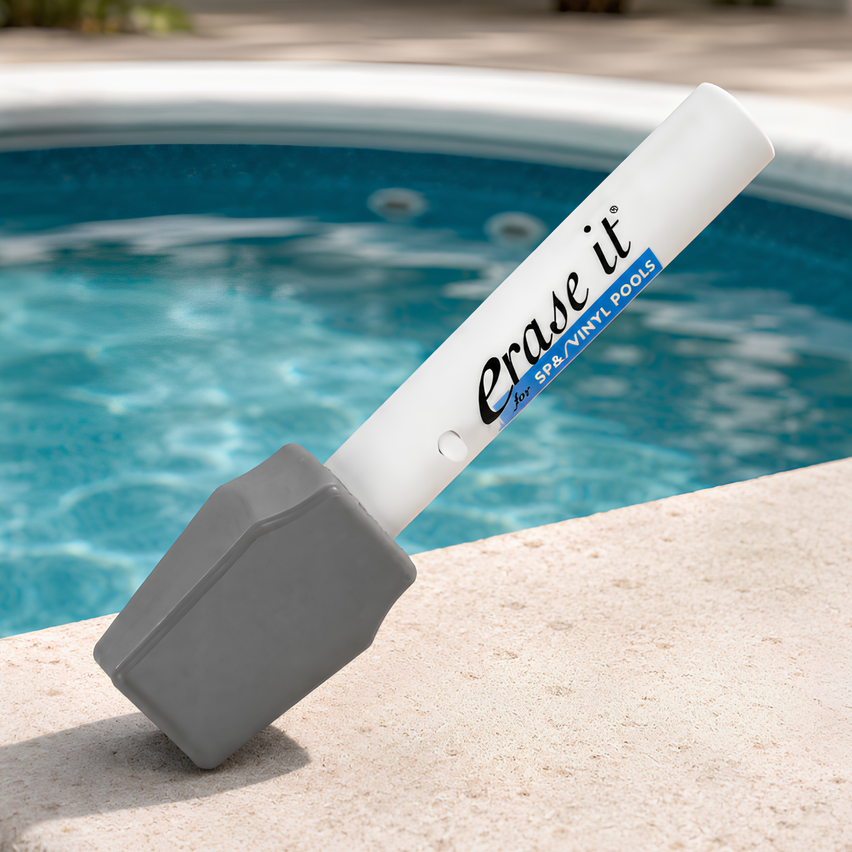 Erase It pool eraser stick resting on the stone coping edge of a clean swimming pool.
