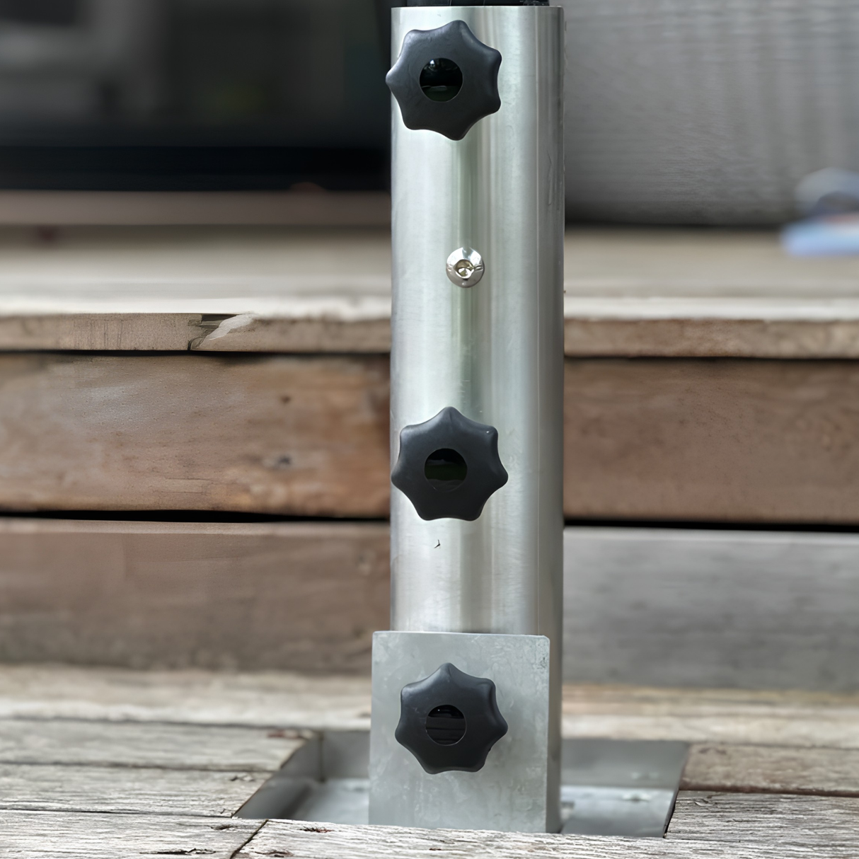 Close-up of an EzyHold Insert 316 marine-grade stainless steel flush-mount umbrella sleeve with a tri-knob locking system installed in a weathered timber deck
