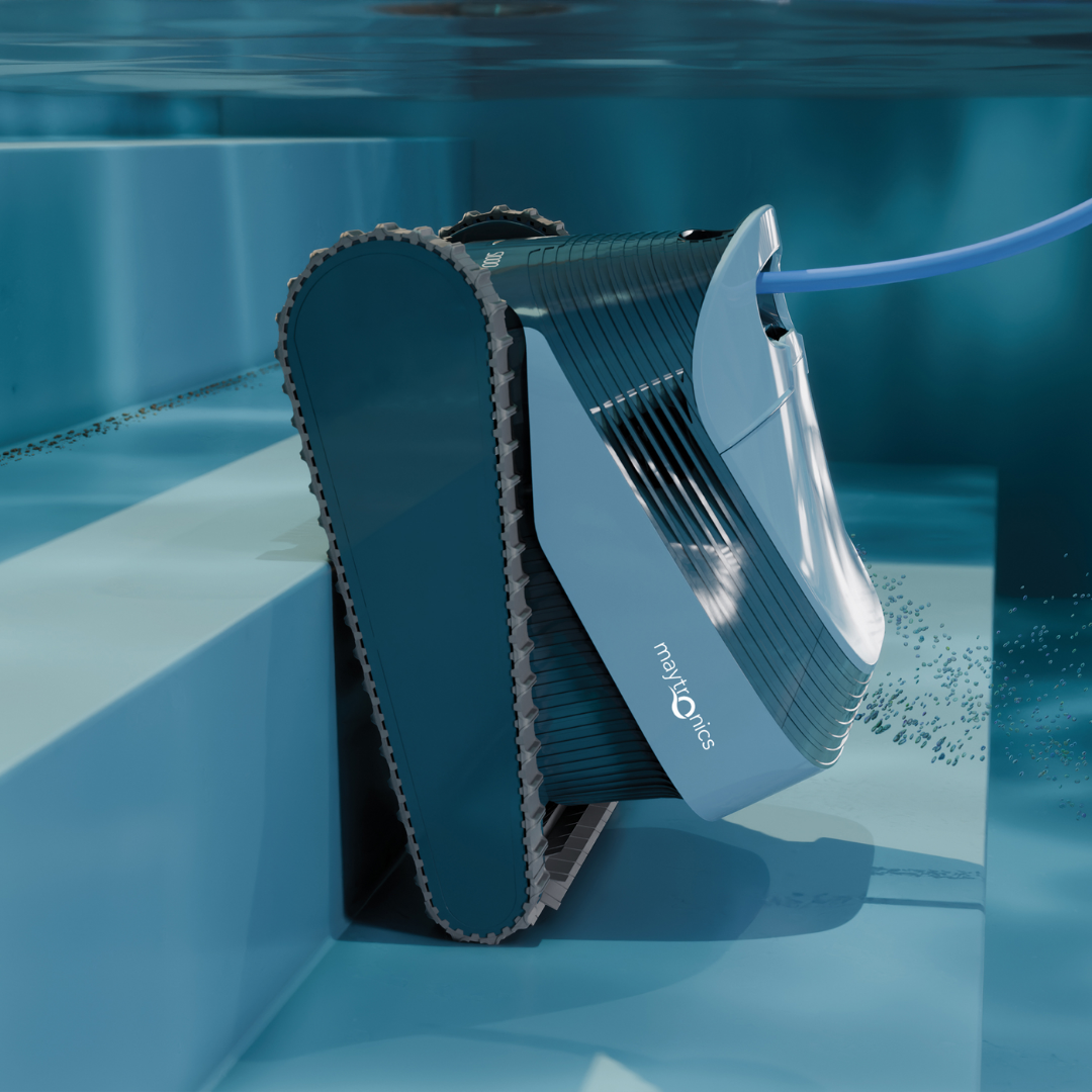 Underwater lifestyle view of the Maytronics Dolphin S1000 robotic pool cleaner climbing pool steps, demonstrating its rubber continuous track drive system, slate blue casing with Maytronics logo, and connected blue power cable.