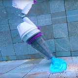 Fully submerged Kokido Telsa 50 cordless pool vacuum cleaning a grey stone tile swimming pool floor with its transparent debris canister and blue brush head visible underwater.