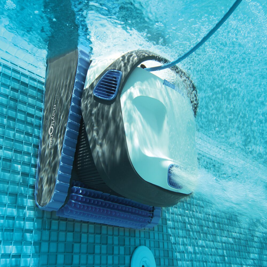 Underwater action view of the white and dark grey Maytronics Dolphin S 150 robotic pool cleaner climbing a blue tiled pool wall with its PowerStream mobility jet shooting water.