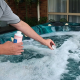pouring a measured capful of Foam Go spa defoamer into spa to instantly break down surface bubbles