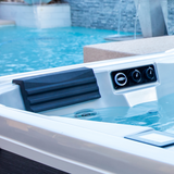 Close-up of a charcoal grey textured headrest pillow installed in an Artesian Elite lounge spa seat next to water control valves and clean spa water.