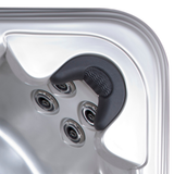 Overhead view of an Artesian Spas Island series neck collar charcoal grey replacement pillow mounted in a contoured silver acrylic hot tub corner above a multi-jet hydrotherapy cluster.