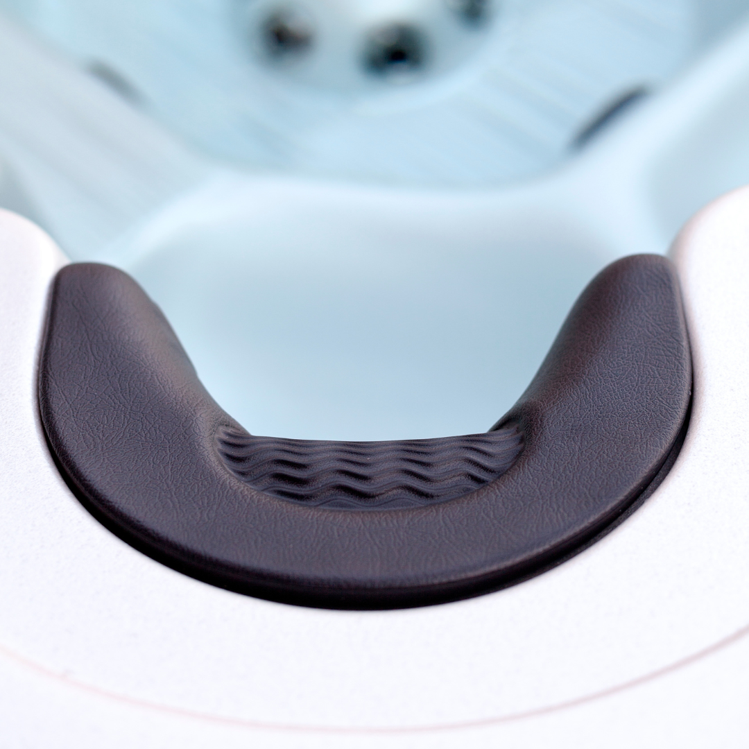 Top-down close-up view of an Artesian Spas Island series charcoal grey neck collar headrest pillow installed in a hot tub, showcasing its curved ergonomic shape and textured wavy center insert.
