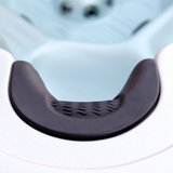 Top-down close-up view of an Artesian Spas Island series charcoal grey neck collar headrest pillow installed in a hot tub, showcasing its curved ergonomic shape and textured wavy center insert.