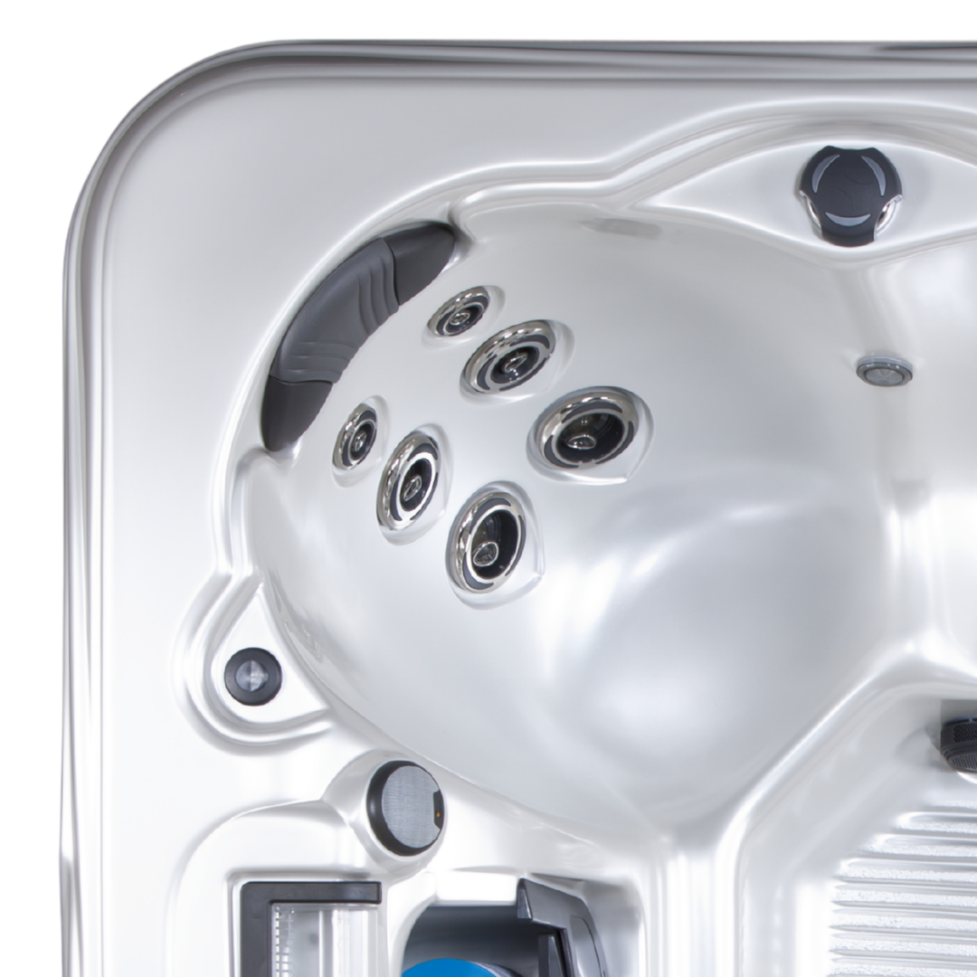 High-angle view of an Artesian Spas Island Lounge charcoal grey headrest pillow mounted inside a contoured silver hot tub shell featuring a multi-jet hydrotherapy cluster.