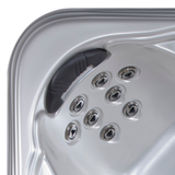 High-angle view of an Artesian Spas Island series charcoal grey waterfall headrest pillow mounted inside a contoured silver acrylic hot tub shell above an eight-jet hydrotherapy configuration.