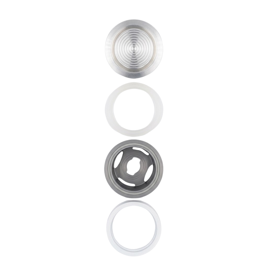 Vertical overhead view showing disassembled components of the Artesian 2-inch Xylex/PVC light lens assembly arranged in sequence: clear ribbed lens face, translucent sealing ring, grey socket housing, and white lock nut.