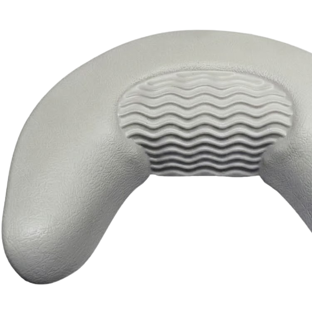 Close-up product shot of a grey curved foam replacement neck headrest pillow for an Artesian spa, detailing the left side contour and the center wavy ridge pad design.