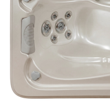 Top-down angle view of a light grey foam lounger headrest pillow installed in an empty cream acrylic hot tub seat, positioned directly above a cluster of adjustable matching grey massage jets.