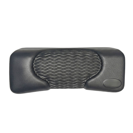 Front product shot of a dark charcoal black rectangular foam replacement lounger headrest pillow for an Artesian hot tub, featuring a textured faux-leather finish, a blank oval emblem insert, and a wavy-ridge center cushion pad against a white background.