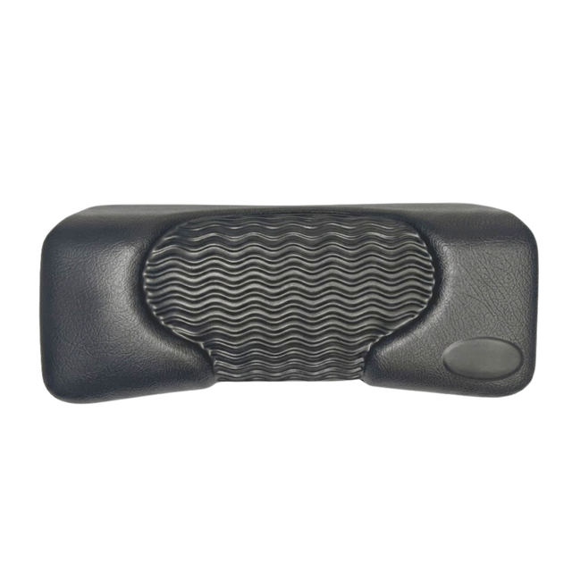 Front product shot of a dark charcoal black rectangular foam replacement lounger headrest pillow for an Artesian hot tub, featuring a textured faux-leather finish, a blank oval emblem insert, and a wavy-ridge center cushion pad against a white background.