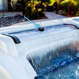 An installed view of an Artesian Spas spillway on and off water valve pointed out by a blue arrow on an active hot tub waterfall feature with cascading water