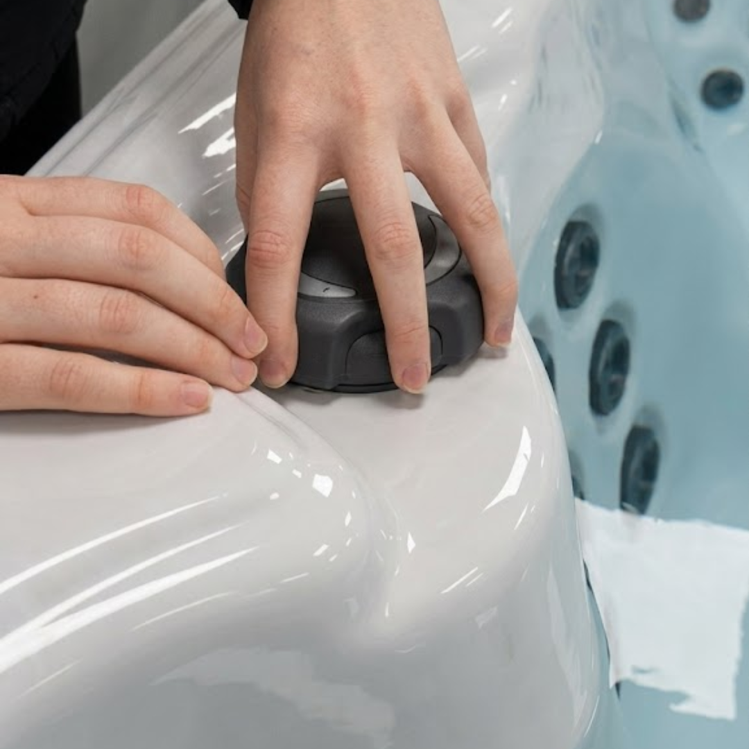 A close up view of hands installing or turning a black 2 inch Artesian Spas diverter valve replacement handle knob on the acrylic top deck rim of a hot tub