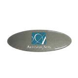 Front view of an oval metallic silver replacement resin dome label for an Artesian Spas headrest pillow, featuring the teal square "A" cursive logo and "ARTESIAN SPAS" branding text.