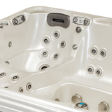 Overhead view of an Artesian Spas Platinum Elite series 12-inch waterfall headrest pillow in dark charcoal gray installed inside a cream-colored hot tub corner above rows of massage jets.