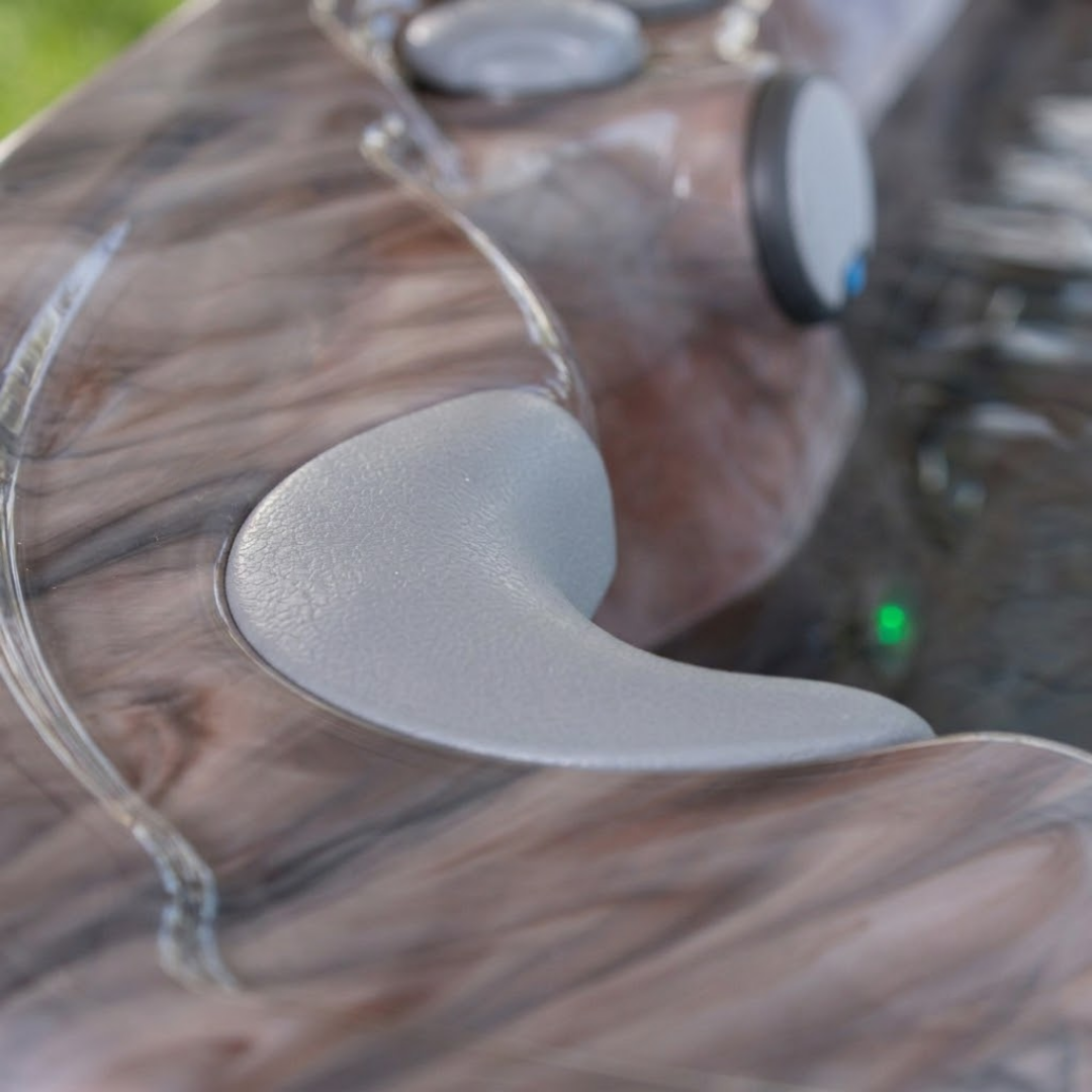 Close-up angled view of an Artesian Spas South Seas series light gray neck headrest pillow installed in a marbled brown acrylic hot tub corner.