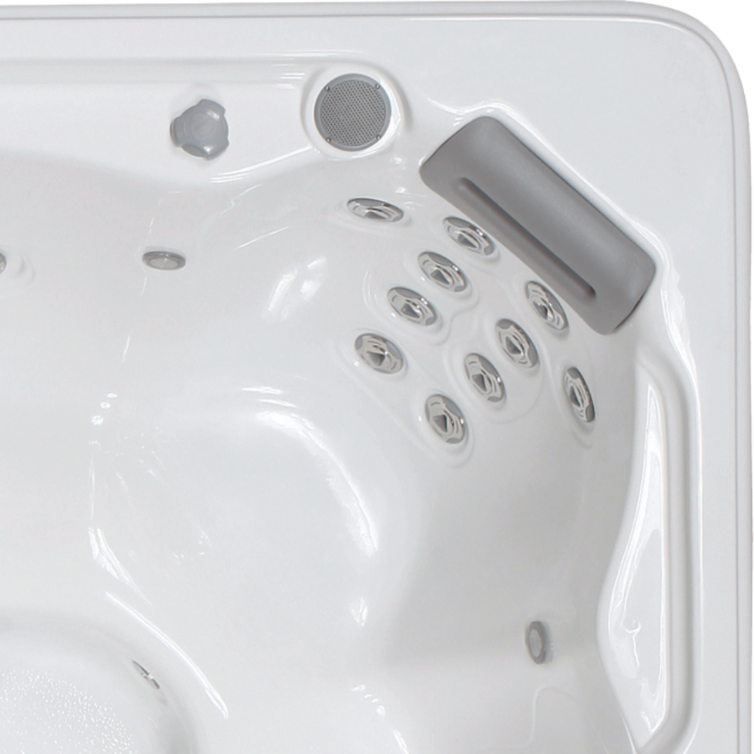 Overhead view of an Artesian Spas South Seas and Tropic Seas series 8-inch waterfall headrest pillow in light gray installed inside a white hot tub corner above rows of massage jets.
