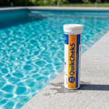 A bottle of Aussie Gold QuikChek5 5-in-1 test strips sitting on a stone poolside coping next to clear blue swimming pool water for regular chemistry checks.