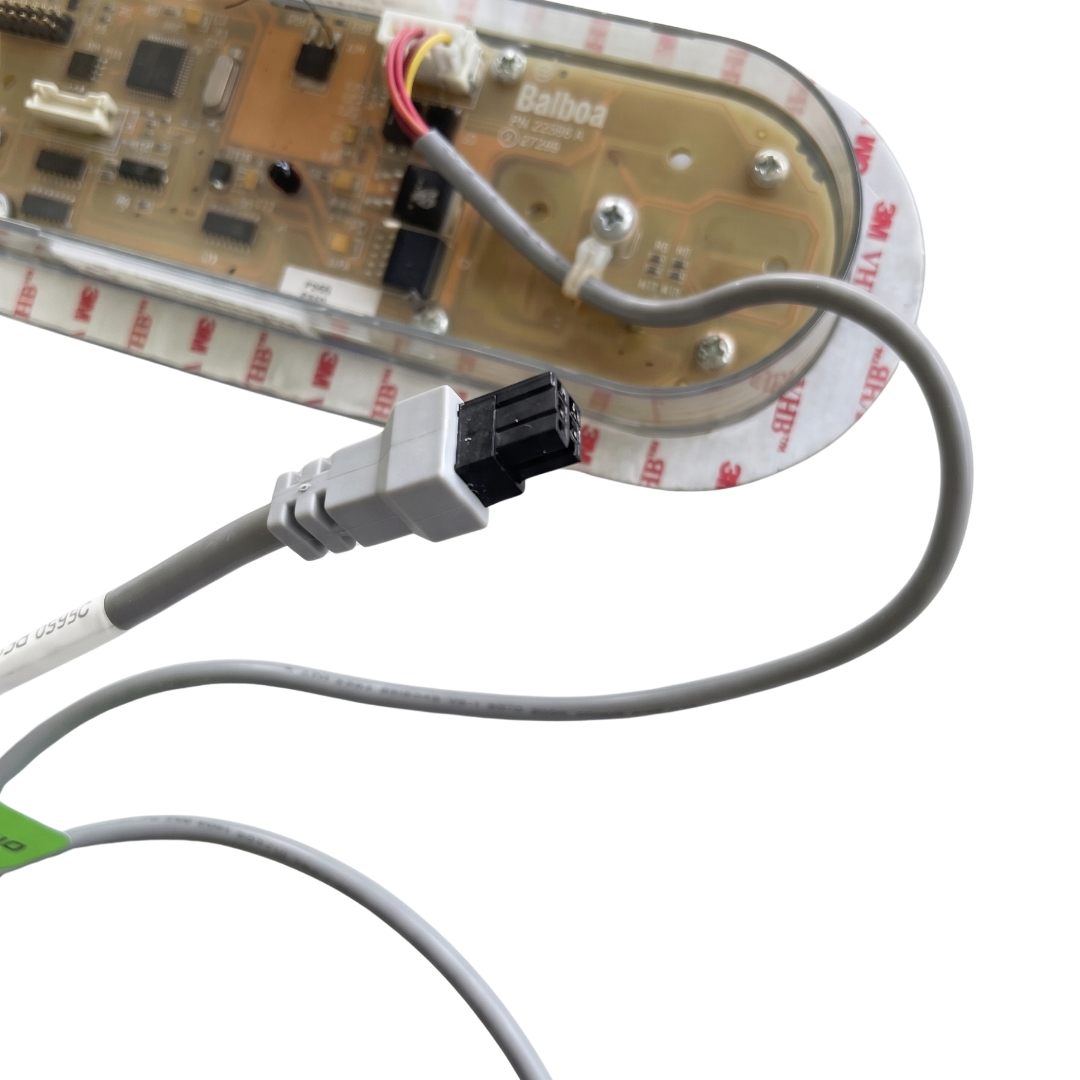 Angled close-up view of a Balboa TP800 TidalFit spa touchpad panel, showing the 4-pin male data cable connection plug in the foreground and the rear translucent circuit board casing with printed part number 22598 A in the background.