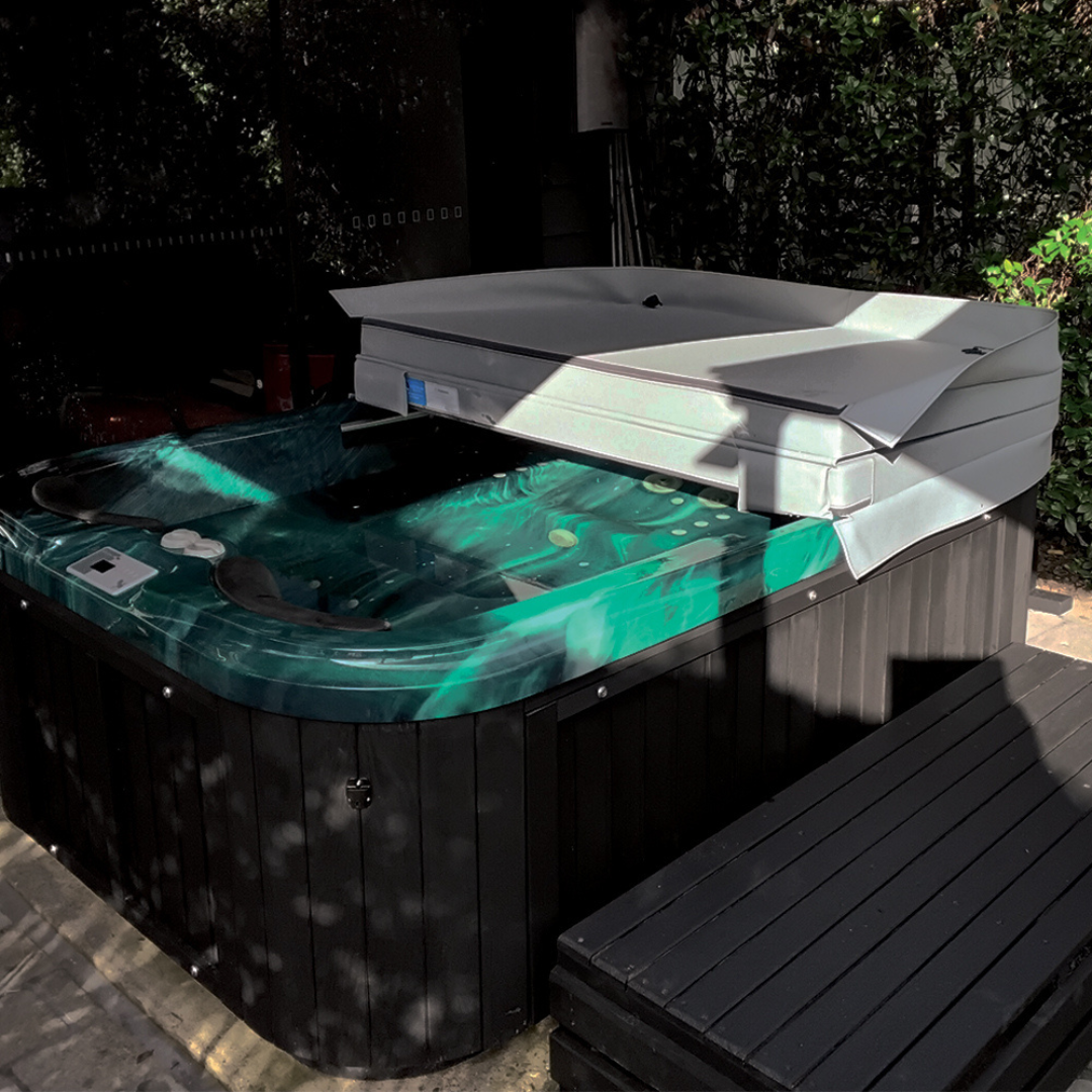 Two-piece replacement spa hard cover shown in a half-open position on an outdoor backyard hot tub.
