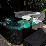 Two-piece replacement spa hard cover shown in a half-open position on an outdoor backyard hot tub.