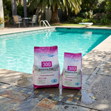 Two bags of BioGuard Balance Pak 300 Calcium Hardness Increaser in 2kg and 4kg sizes sitting poolside on a tiled stone patio, used to raise pool calcium levels.