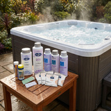 BioGuard SPA Eco-Spa chlorinator chemical startup kit with Armour sanitiser, Perfect Balance, water balancers, Spa Purity sachets, and test strips displayed on a wet wooden side table next to a steaming, bubbling outdoor hot tub.