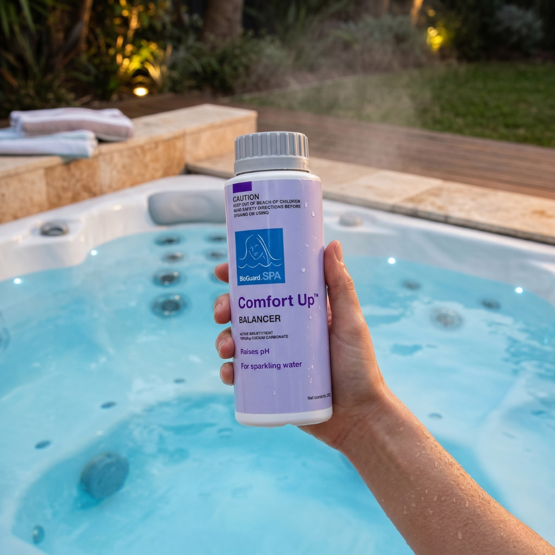 A person holding a 500g bottle of BioGuard Spa Comfort Up pH Increaser over a clean, bubbling outdoor spa at night to raise water pH and prevent equipment corrosion.