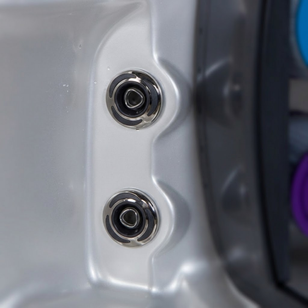 Two C-Helix 3 Directional SS spa jets installed vertically aligned in the contoured acrylic shell of a hot tub, showing their stainless steel bezels with black crescent accents against the silver-grey spa interior.