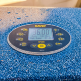 An angled view of an operational Davey SP1200 oval spa touchpad controller mounted on a blue textured hot tub rim, displaying a digital reading of 36.00°C on its illuminated LCD screen.