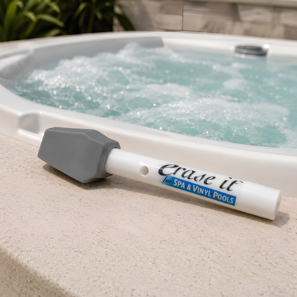 Erase It for Spa and Vinyl Pools stain eraser stick resting on the edge of a bubbling white acrylic hot tub.