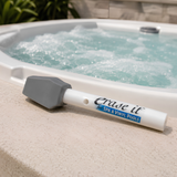 Erase It for Spa and Vinyl Pools stain eraser stick resting on the edge of a bubbling white acrylic hot tub.