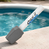 Erase It pool eraser stick resting on the stone coping edge of a clean swimming pool.