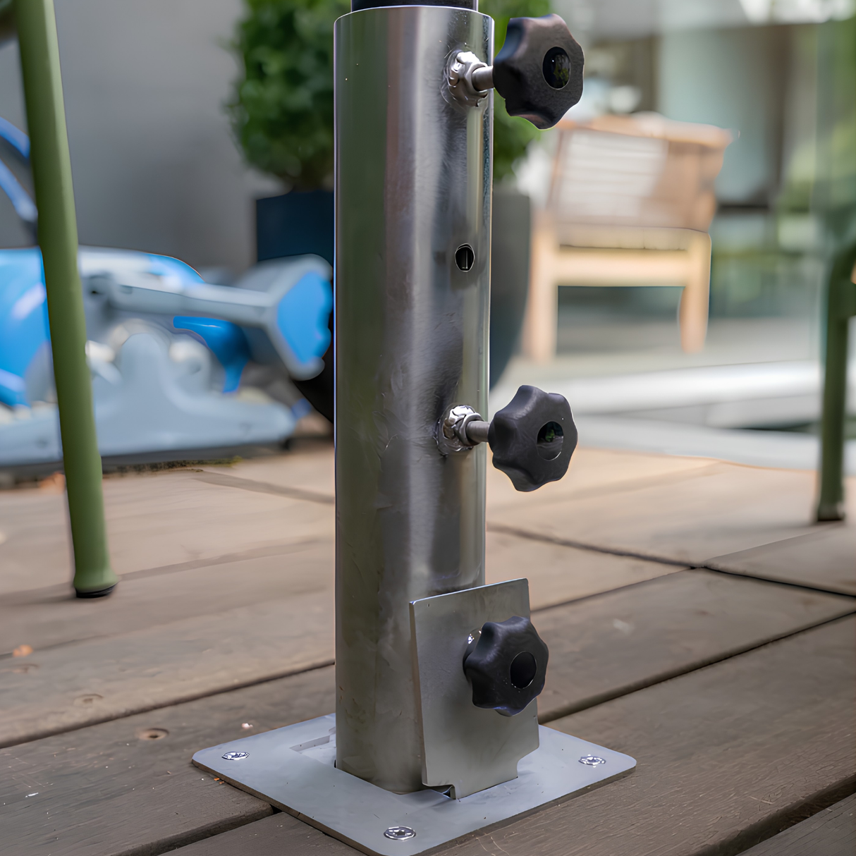 Close-up of a stainless steel EzyHold deck mount umbrella sleeve featuring three black locking tightening knobs installed on an outdoor timber pool deck.