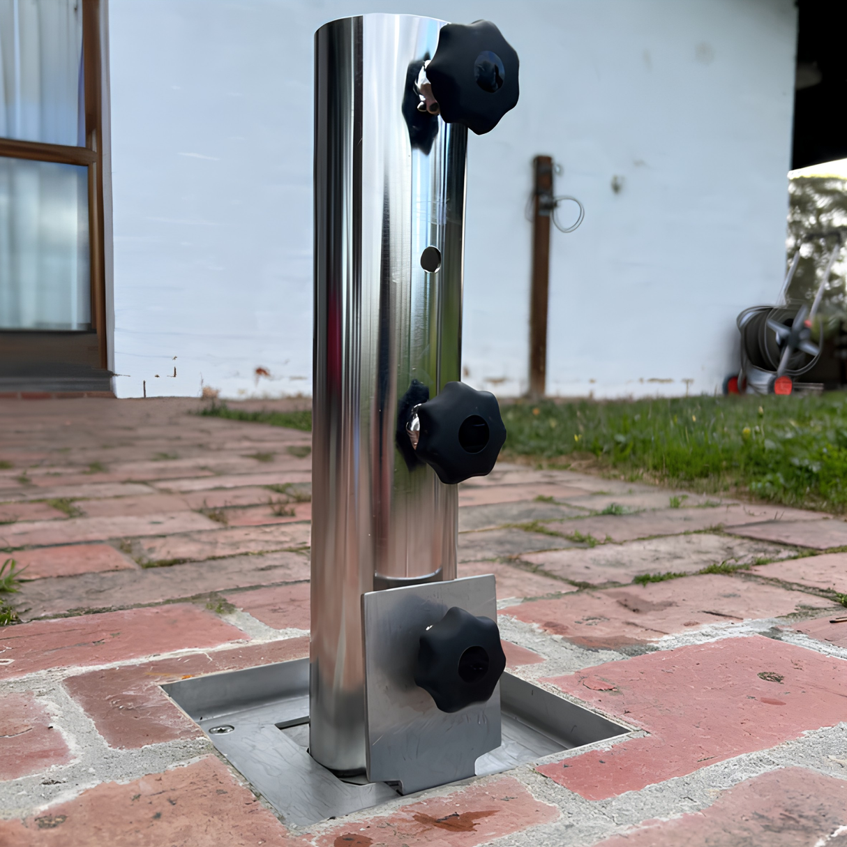 EzyHold Insert 316 marine-grade stainless steel flush-mount umbrella holder installed into a brick paver courtyard with the tri-knob stabilizing sleeve attached.