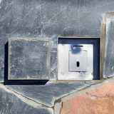 Top-down view of an EzyHold Insert flush-mount umbrella holder base installed in natural stone slate paving, shown next to its matching slate-filled insert lid.