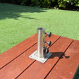Heavy-duty 316 marine-grade stainless steel EzyHold Top Mount low-profile umbrella holder sleeve bolted flush onto a rich reddish-brown timber outdoor deck