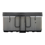 Straight-on view of a closed dark grey hot tub cover with a black metal gas spring-assisted lifter mechanism mounted centered on the side of a grey wood-paneled spa, isolated on a white background.