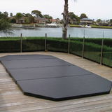 Custom-made black hard cover installed on an in-ground swim spa built into a timber deck overlooking a canal backyard.