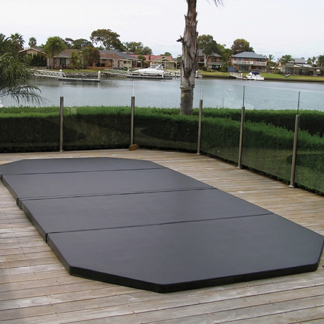 Custom-made black hard cover installed on an in-ground swim spa built into a timber deck overlooking a canal backyard.
