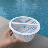 Person holding a white plastic Hayward SPX1094FA pool skimmer basket replacement by a swimming pool edge during routine maintenance.